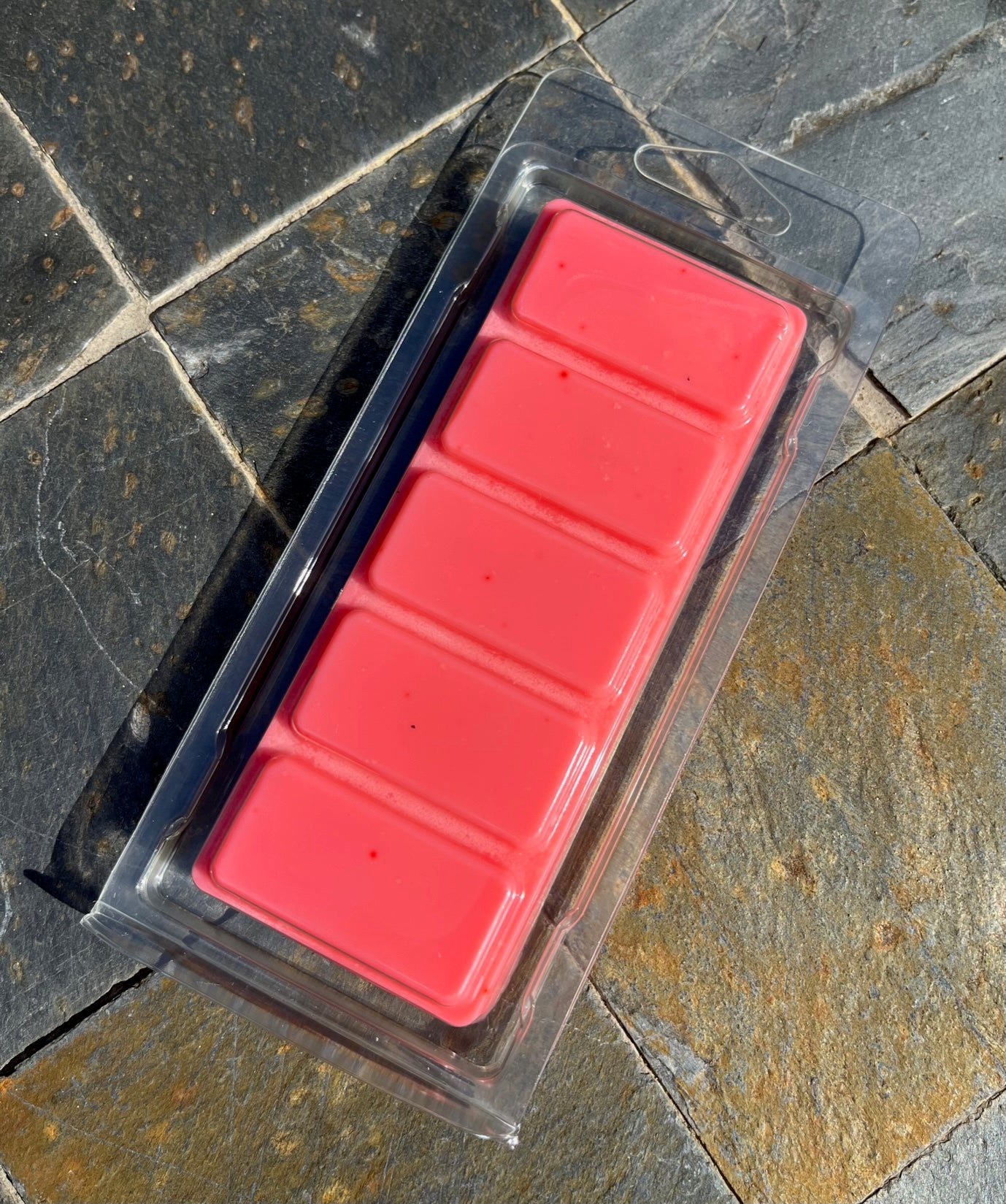 <img src="Cranberry Apple Snapbar" alt="Package of five red wax melts in a clear plastic container, placed on a mosaic surface.">
